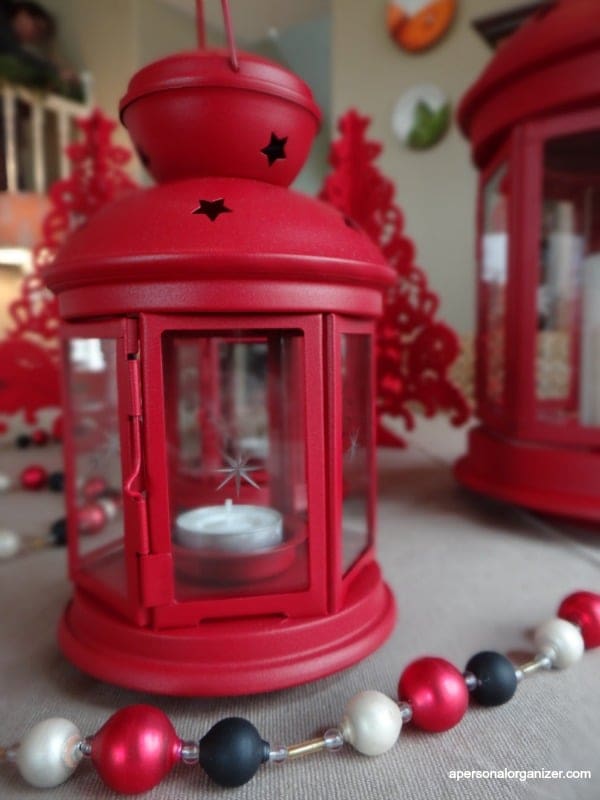 {Ornamentos simples e as lanternas vermelhas transformam a nossa mesa de jantar em uma peça da decoração natalina}