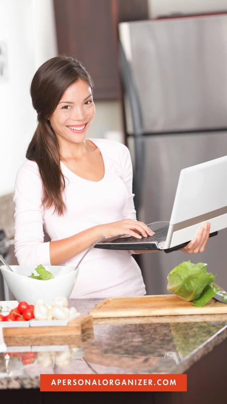 Woman in the kitchen planning the menu on a laptop