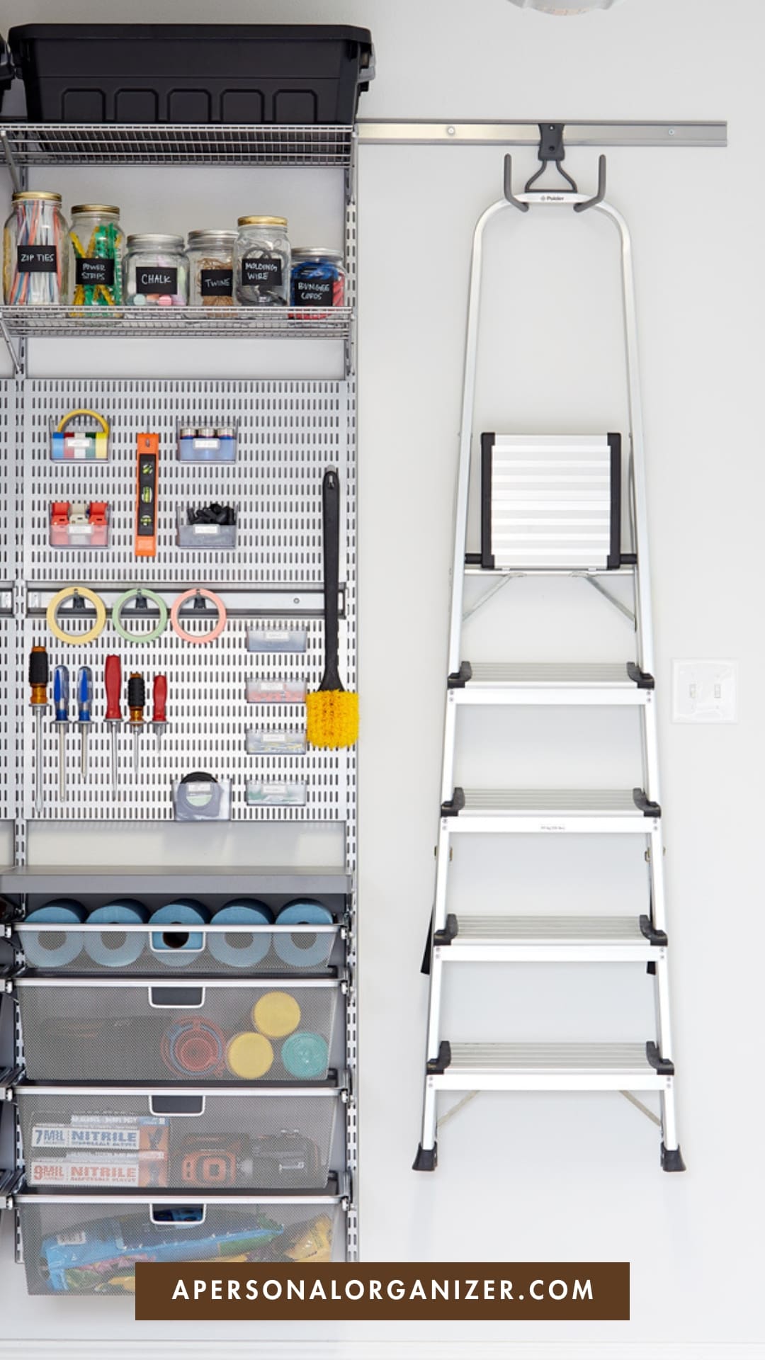 A neatly organized garage wall with shelves holding tools, paint cans, and storage bins. A silver step ladder is mounted on the wall next to the shelving. At the bottom, a label reads "APERSONALORGANIZER.COM".